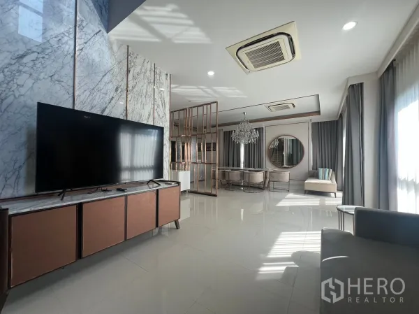 Detached House for rent or sale in Prawet, Bangkok - Spacious open-plan living and dining with large TV, marble feature wall and recessed lighting.