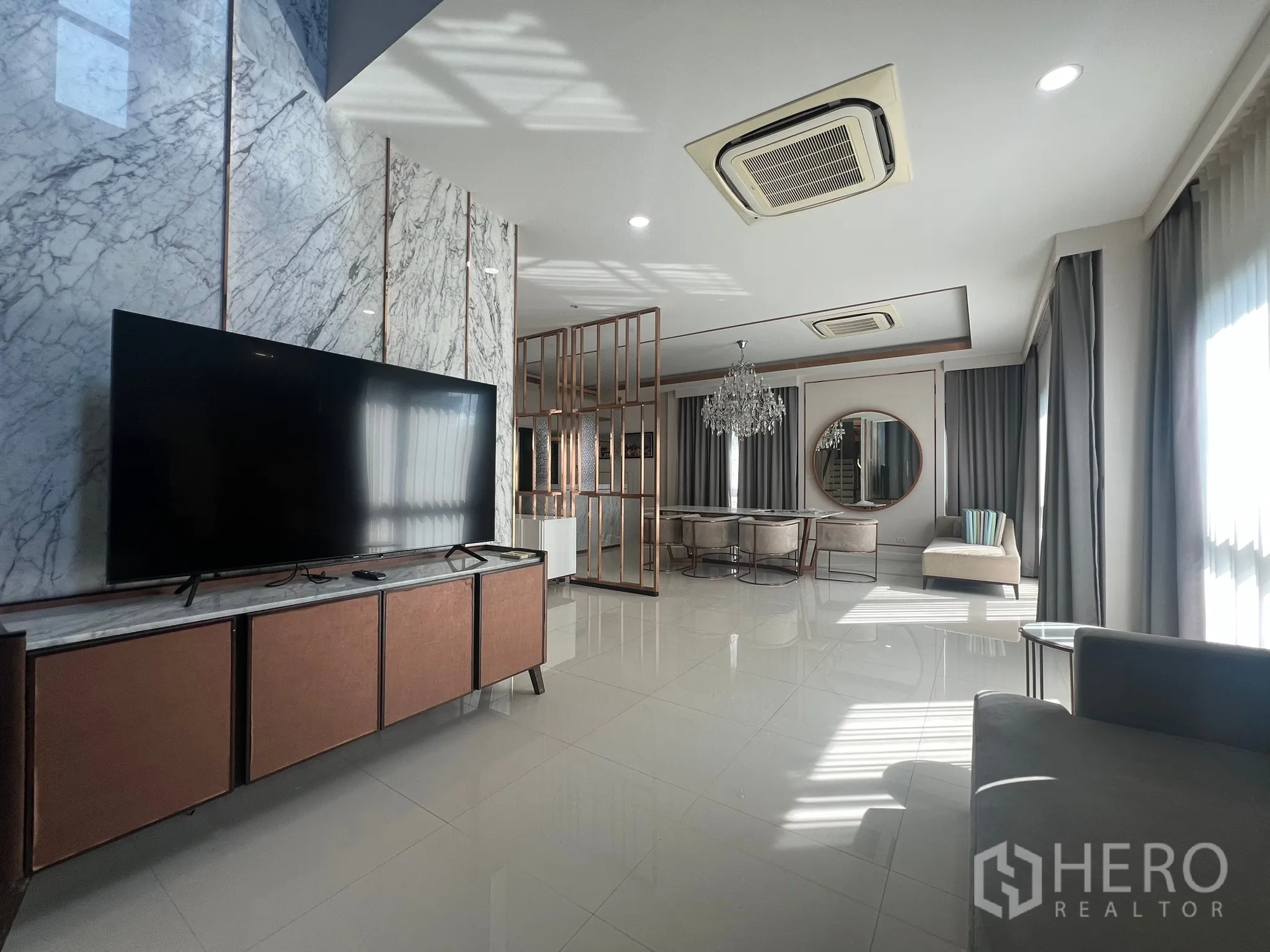Detached House for rent or sale in Prawet, Bangkok - Spacious open-plan living and dining with large TV, marble feature wall and recessed lighting.