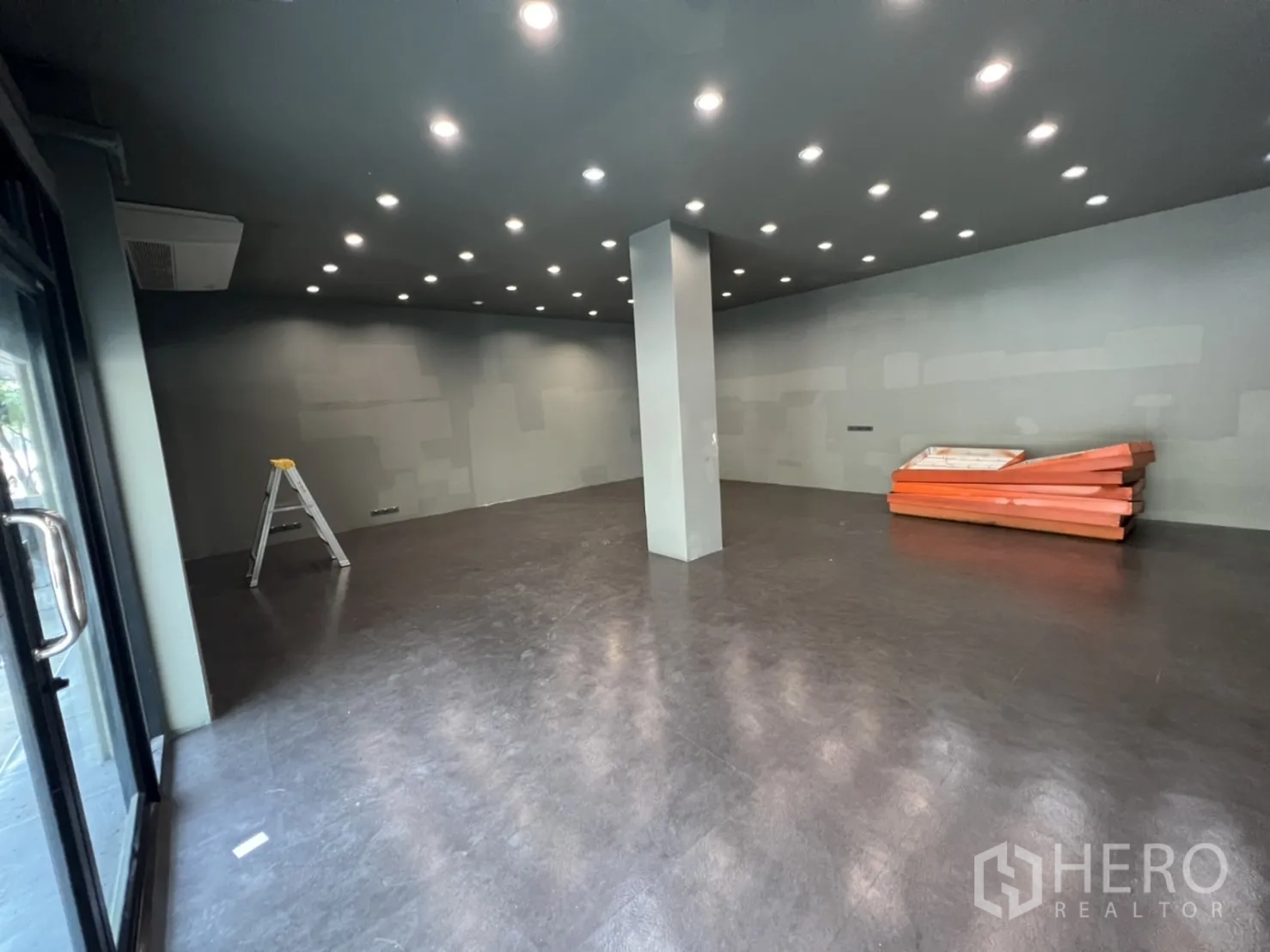 Shophouse for rent in Phra Khanong, Bangkok - Spacious ground-floor retail area with dark flooring, a central column and rows of recessed LED downlights.