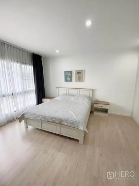 联排别墅 出租在Prawet, Bangkok - 采光充足的卧室，大窗帘墙、双人床与床头柜。