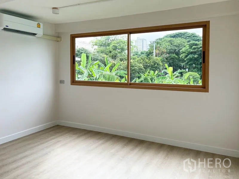 Townhouse for rent or sale - Bright bedroom with wide window and green treetop views, light wood flooring and air conditioner.