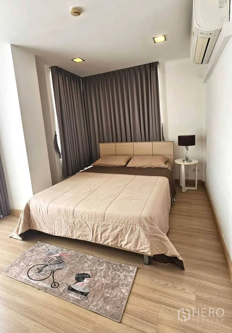 公寓 出租在Watthana, Bangkok - 转角主卧，米色床品、遮光窗帘与床头台灯。