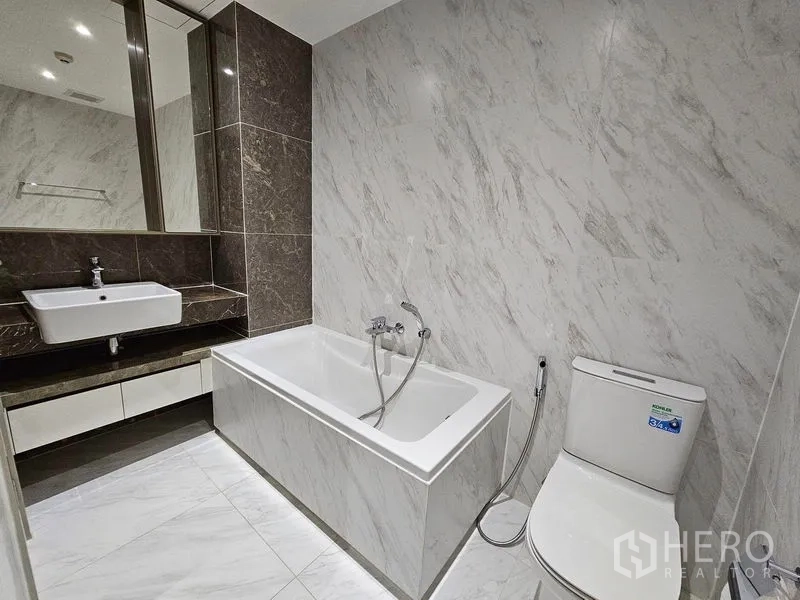 Condominium for rent or sale - Bathroom featuring vanity with mirror, soaking tub, and toilet.
