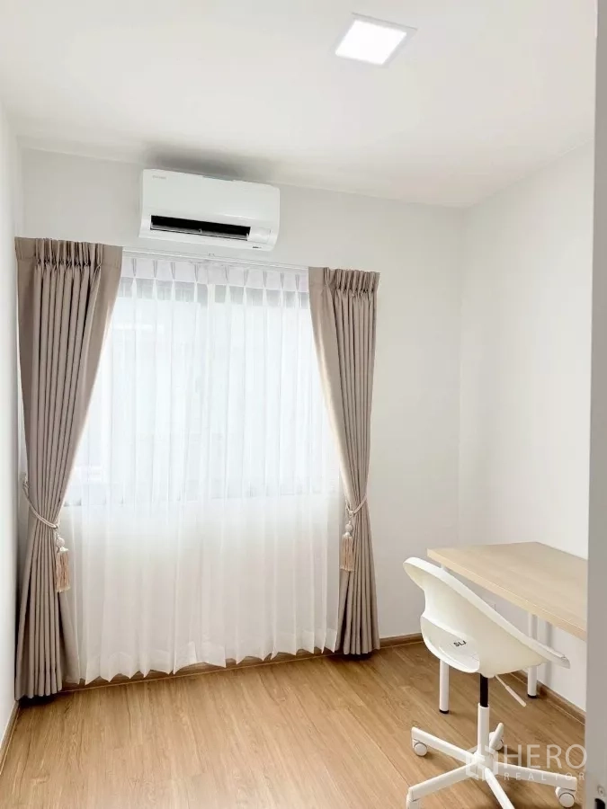 联排别墅 出租在Bang Phli, Samut Prakan - 第三卧/书房，带书桌、椅子、空调和纱帘。