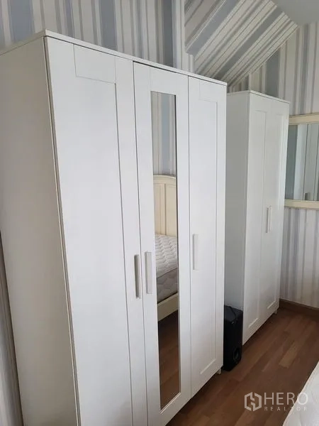 联排别墅 出租在Wang Thonglang, Bangkok - 卧室内白色衣柜，带镜面门与条纹墙纸