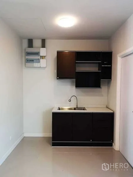 Home Office for rent in Bang Phli, Samut Prakan - Compact pantry with dark cabinets and stainless sink in a bright room.