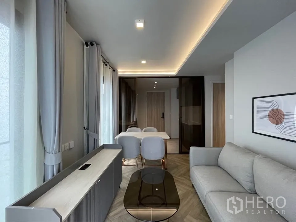 คอนโด for rent in Watthana, Bangkok - พื้นที่นั่งเล่นมีโซฟาสีเทา ชั้นวางทีวี ชุดโต๊ะทานอาหาร และหน้าต่างบานใหญ่พร้อมผ้าม่าน