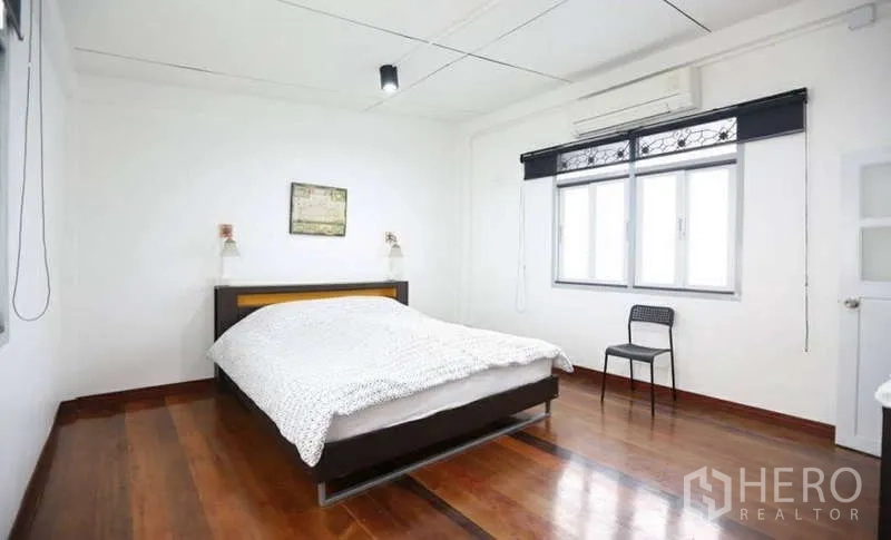 Home Office for rent in Khlong Toei, Bangkok - Air-conditioned bedroom with double bed, large window, and wooden flooring.