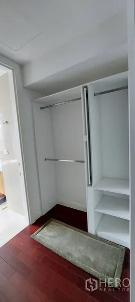 公寓 出租在Pathum Wan, Bangkok - 步入式衣帽间，白色内置层架与挂杆，靠近浴室入口，木地板。