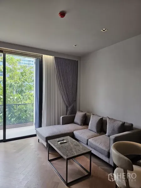 คอนโด ให้เช่าในWatthana, Bangkok - โซฟามุมและโต๊ะกลางหินอ่อนข้างหน้าต่างสูงจรดเพดานมองเห็นความเขียวขจี