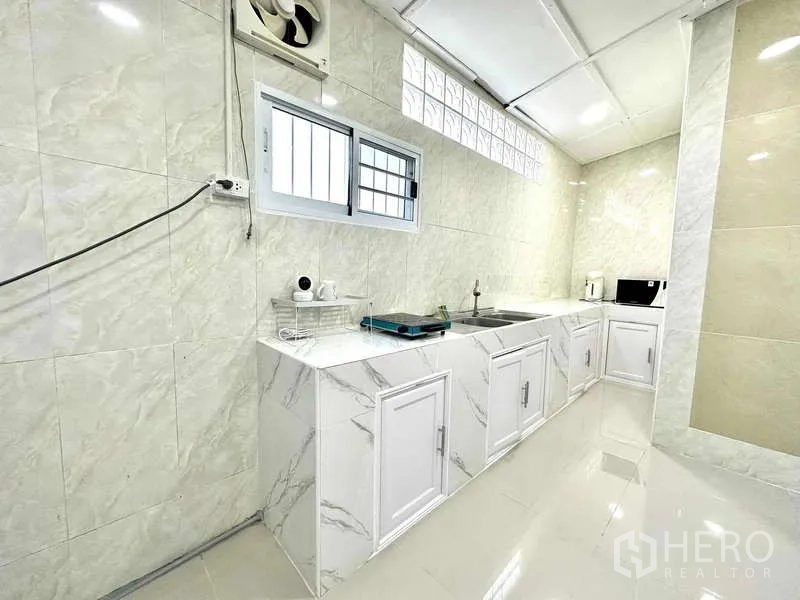 Detached House for rent in Lat Krabang, Bangkok - Kitchen close-up of marble-look countertops, double sink and ventilation fan.