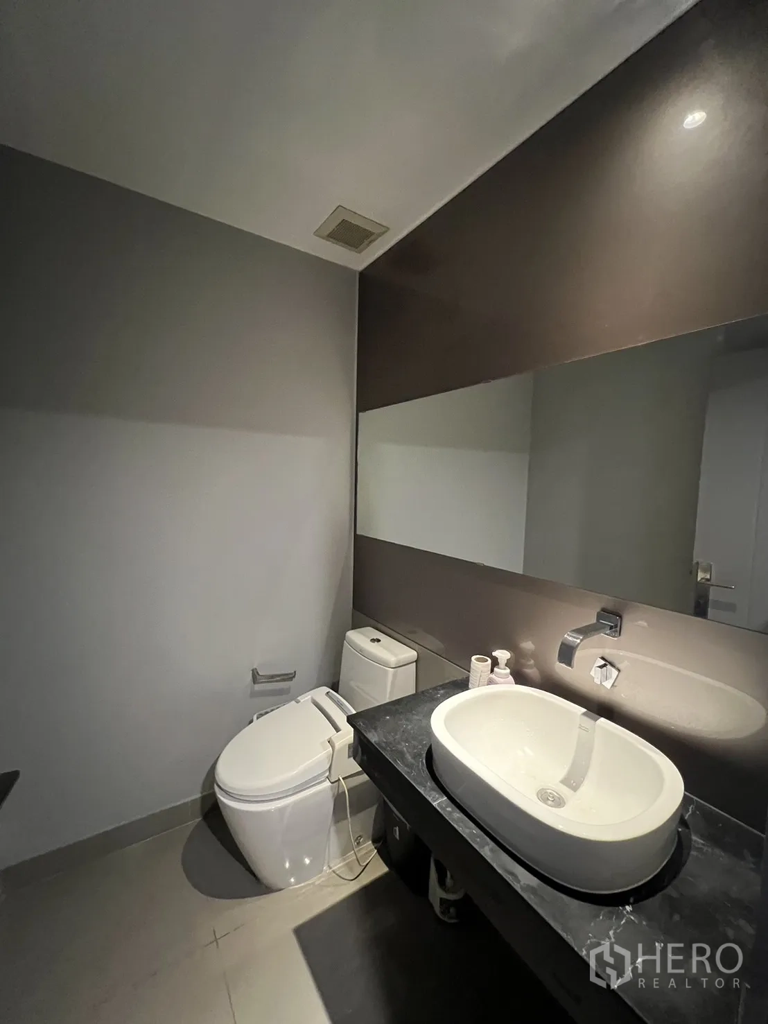 Townhouse for rent in Lat Phrao, Bangkok - Guest bathroom with wide mirror, vessel sink on black counter and modern toilet.
