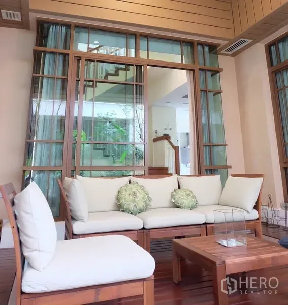 บ้าน ให้เช่าในWatthana, Bangkok - เฉลียงมีหลังคาพร้อมชุดโซฟาไม้บุผ้าและประตูกระจกเปิดสู่ตัวบ้าน
