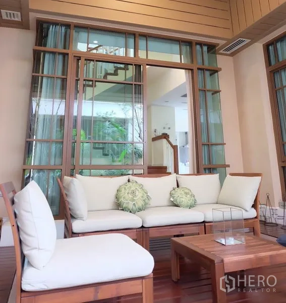 บ้าน ให้เช่าในWatthana, Bangkok - เฉลียงมีหลังคาพร้อมชุดโซฟาไม้บุผ้าและประตูกระจกเปิดสู่ตัวบ้าน