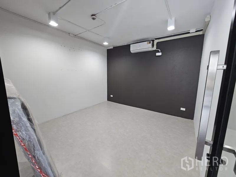 Retail Space for rent - Enclosed room with dark feature wall, split-type air conditioner, and bright ceiling spotlights.