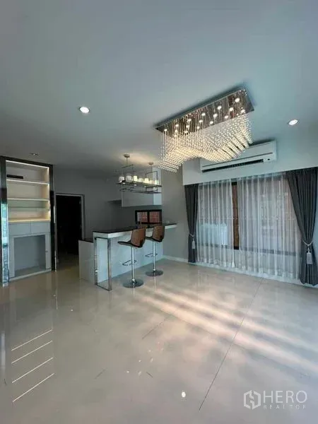 独立式住宅 出售在Prawet, Bangkok - 明亮客餐一体空间，设中岛与水晶吊灯，落地窗帘。