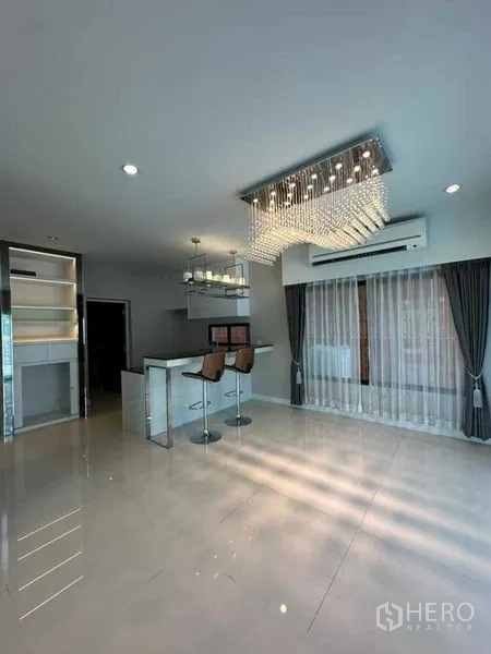 独立式住宅 出售在Prawet, Bangkok - 明亮客餐一体空间，设中岛与水晶吊灯，落地窗帘。