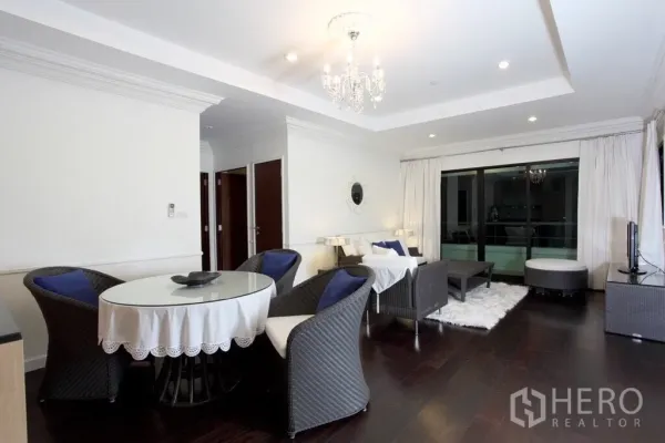 Condominium for rent in Sathon, Bangkok - Open-plan living and dining area with chandelier lighting, dark wood floors, and access to a large balcony.
