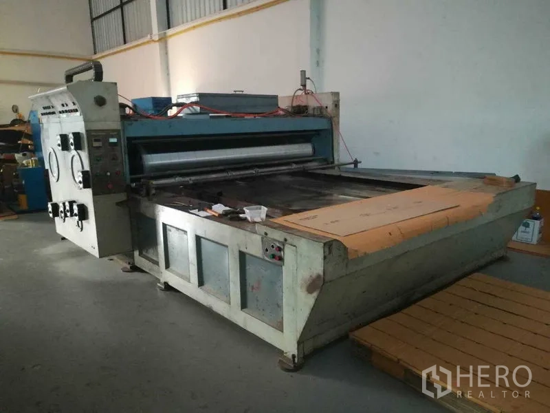 工厂 for sale in Bang Len, Nakhon Pathom - 正面可见带滚筒与进料台的绿色加工机组，位于仓库内。