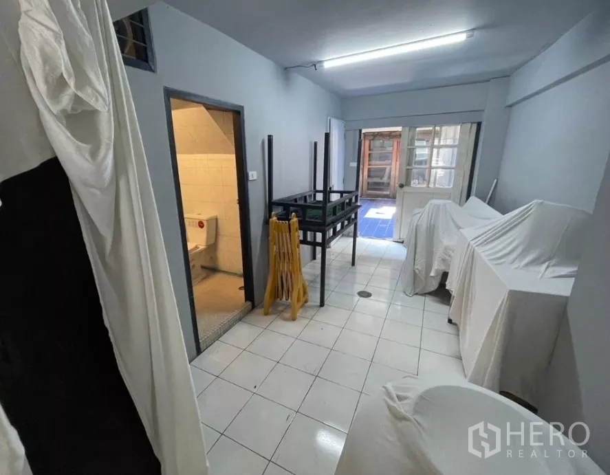店屋 出租在Watthana, Bangkok - 后侧工作区带卫生间入口与玻璃后门，地面为瓷砖。