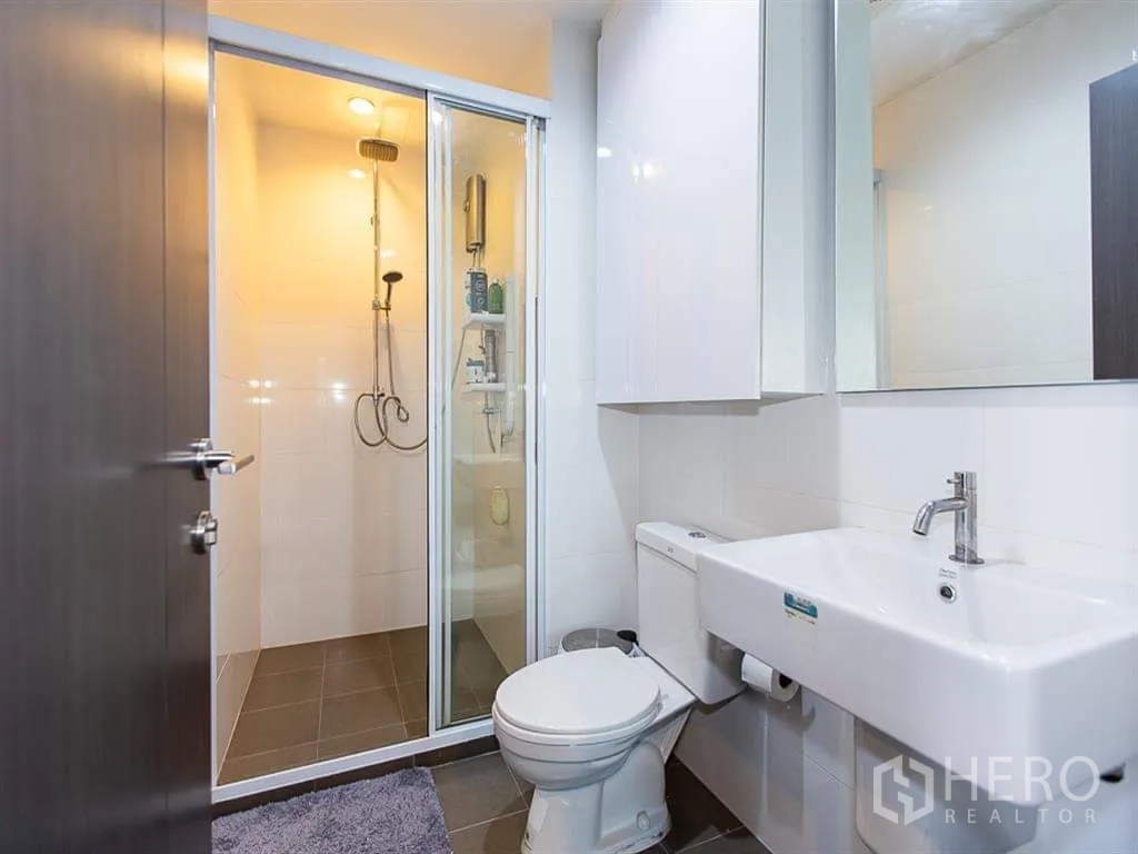 Condominium for rent or sale in Watthana, Bangkok - Modern bathroom with glass shower enclosure, toilet and vanity sink.