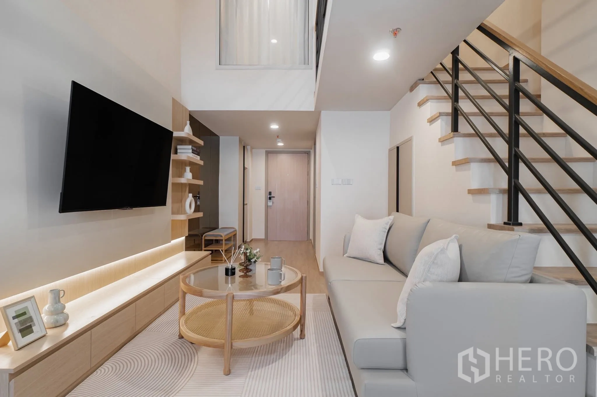 คอนโด for rent in Bang Rak, Bangkok - ห้องนั่งเล่นเพดานสูงสไตล์ลอฟต์พร้อมโซฟา ทีวีติดผนัง ตู้ไม้ โต๊ะกลางกระจก และบันไดขึ้นชั้นลอย