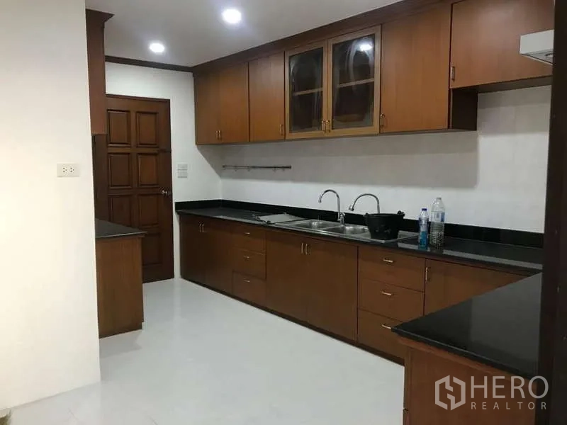 公寓 出售在Watthana, Bangkok - 独立厨房，长黑色台面与全套木质橱柜。