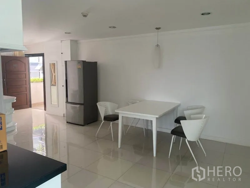 Condominium for rent in Watthana, Bangkok - Dining area with white table and four chairs next to a stainless-steel refrigerator.