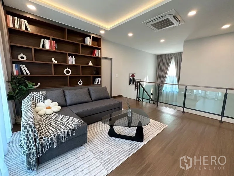Detached House for rent or sale in Bang Phli, Samut Prakan - Library-style lounge with sectional sofa and floor rug.