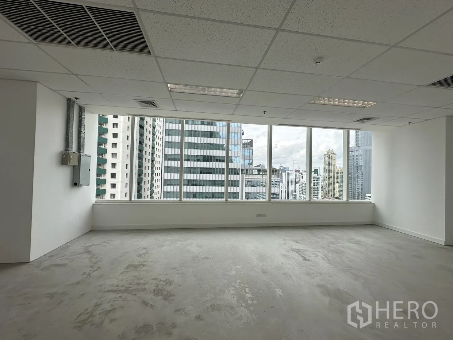 办公室 for rent in Watthana, Bangkok - 未配家具的办公室，矿棉板吊顶与条形灯具，落地窗外为城市天际线。