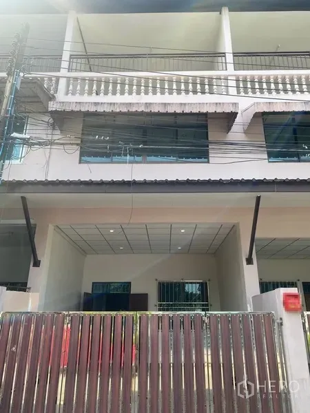 Townhouse for rent in Suan Luang, Bangkok - Three-storey townhouse facade with gated carport, balconies and large windows in On Nut, Bangkok.