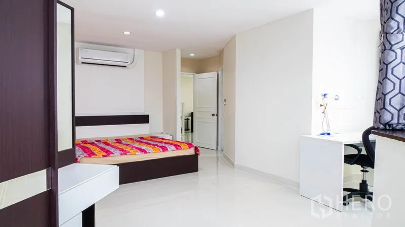 Condominium for rent or sale in Khlong Toei, Bangkok - Large bedroom with bed, study desk, wardrobe and air conditioning.