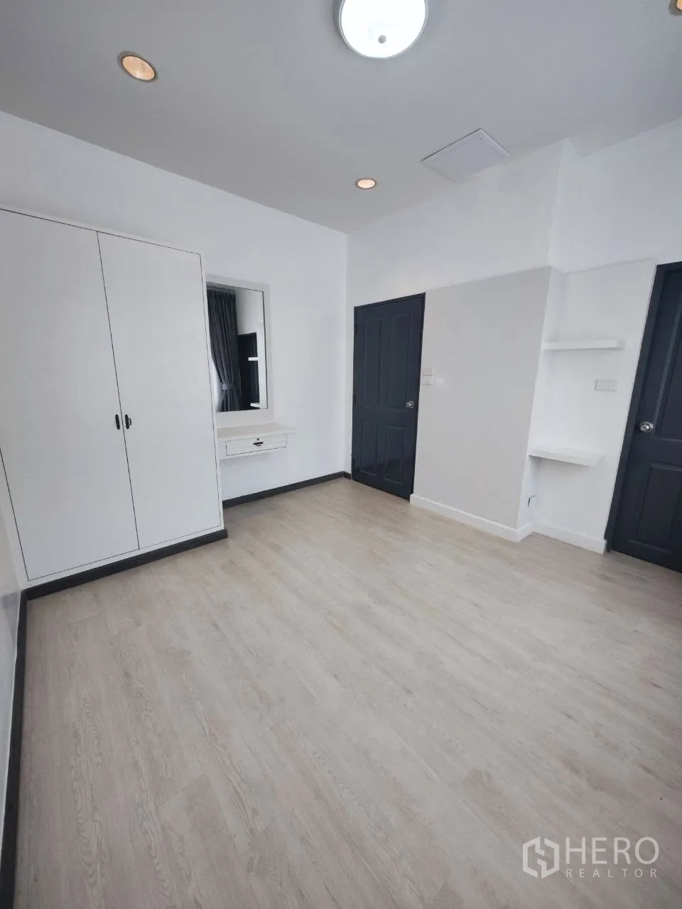 Home Office for rent in Bang Na, Bangkok - Light-filled room with built-in wardrobe, vanity and pale wood flooring.