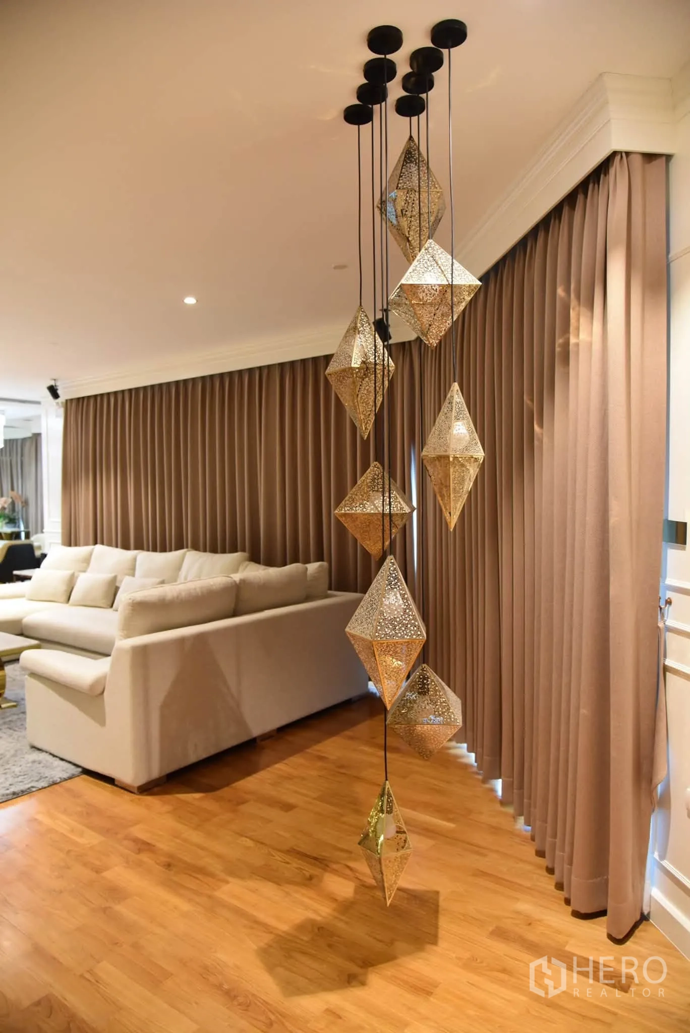 คอนโด for sale in Khlong San, Bangkok - โคมไฟแขวนดีไซน์เด่นข้างโซฟาตัวแอลและผ้าม่านสูงเต็มผนัง