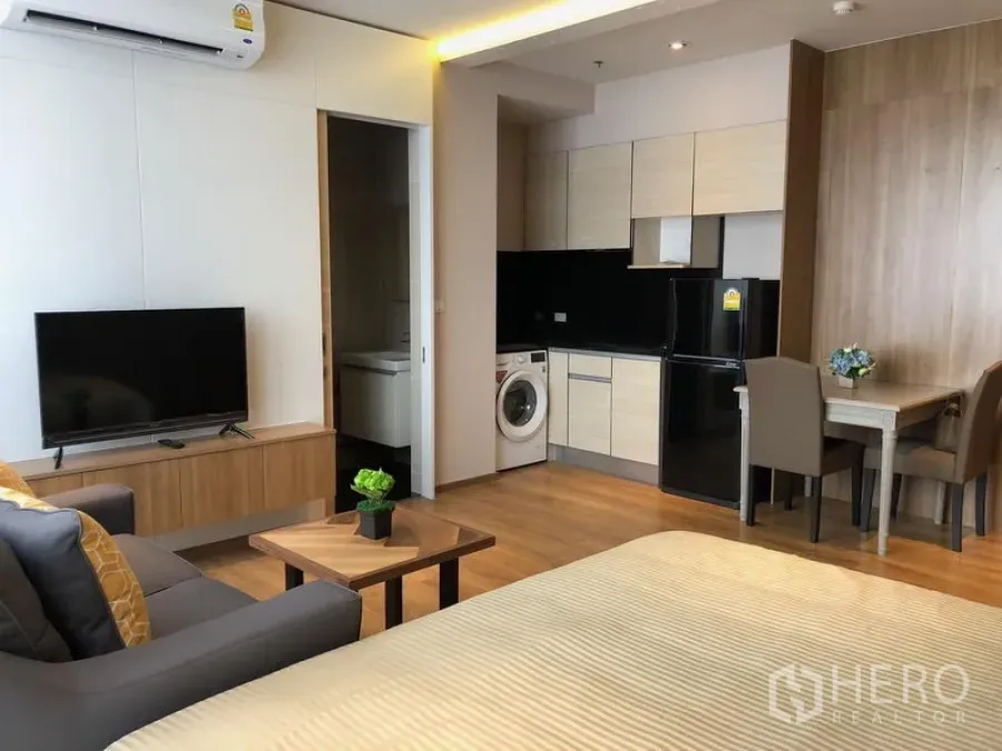 公寓 出租在Khlong Toei, Bangkok - 现代化单间公寓内景，带小厨房、洗衣机、电视和用餐角。