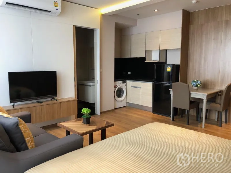 公寓 出租在Khlong Toei, Bangkok - 现代化单间公寓内景，带小厨房、洗衣机、电视和用餐角。