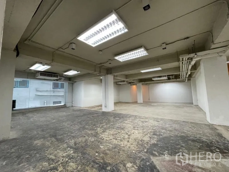 Office Space for rent in Ratchathewi, Bangkok - Wide view of open office with multiple ceiling lights, AC units and concrete flooring.