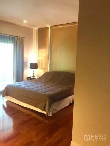 Detached House for sale in Lat Krabang, Bangkok - Second bedroom featuring warm wood flooring, bed and bedside lamp.