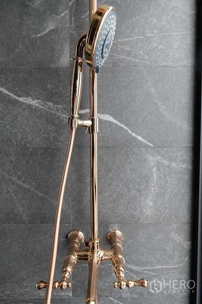 Condominium for sale - Close-up of gold handheld shower on a gray stone wall.