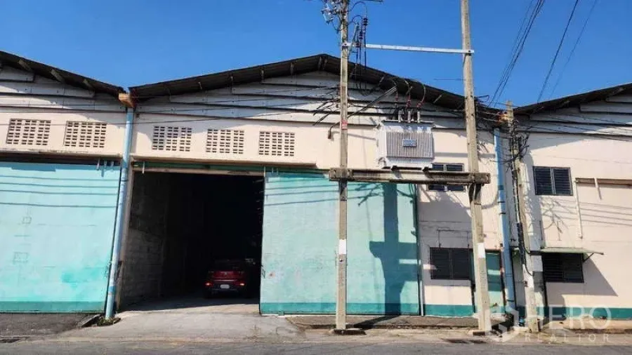 Warehouse for rent in Nong Khaem, Bangkok - Street-facing warehouse facade with wide sliding doors and an on-site power transformer.