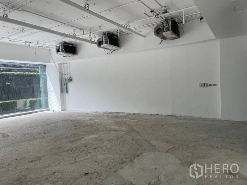 零售空间 出租在Watthana, Bangkok - 近景展示白色墙面、吊装空调与配电箱，适合二次装修。