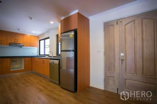 Condominium for rent or sale in Watthana, Bangkok - Entry foyer with L-shaped kitchen, wood cabinets, stainless fridge and dishwasher at Las Colinas Asoke.