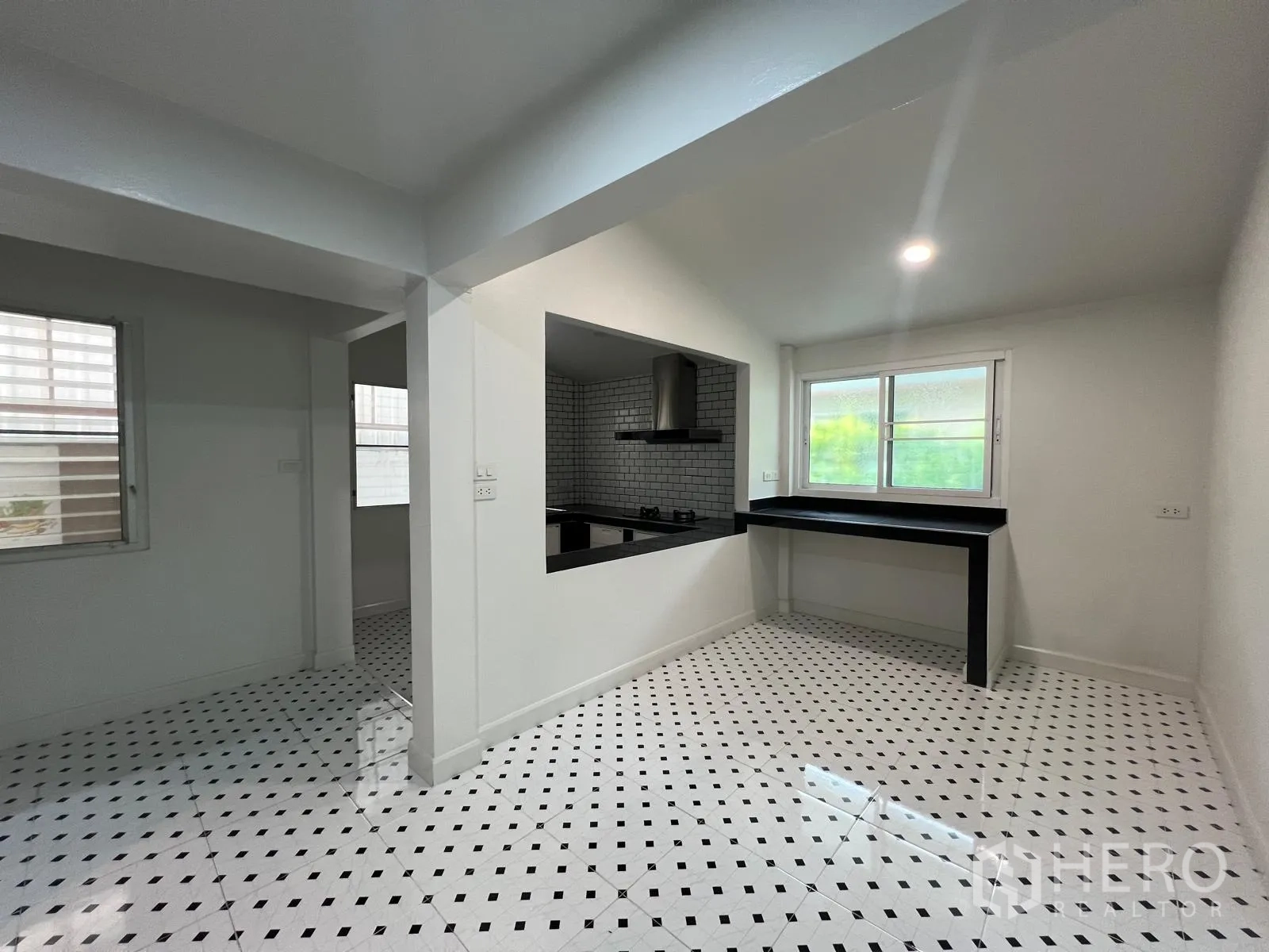 Detached House for rent in Saphan Sung, Bangkok - Breakfast area beside a kitchen pass-through with black counter and patterned tile floor.