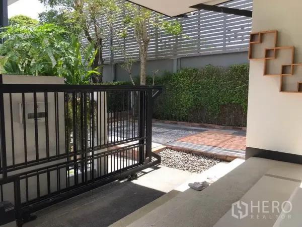 Detached House for rent in Bang Kapi, Bangkok - Front sliding gate and driveway bordered by greenery and a privacy fence at a Bangkok detached home.