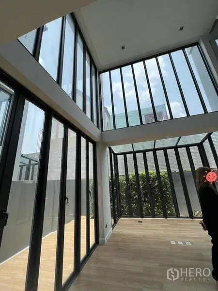 带办公室的家 出售在Wang Thonglang, Bangkok - 挑高客厅配落地玻璃与木地板，面向私密绿篱，现代家办一体空间。