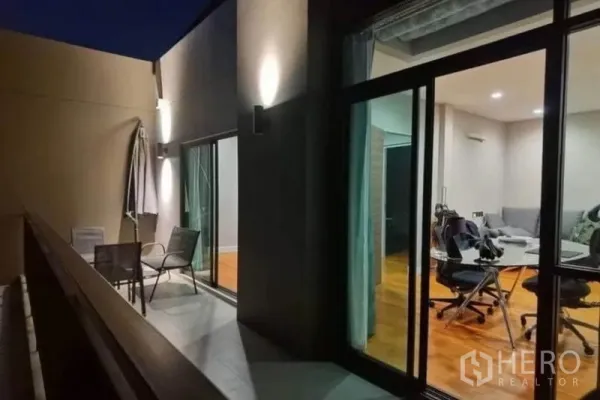 Detached House for rent - Night view of the balcony with wall lights, outdoor chairs and sliding doors opening to living areas.