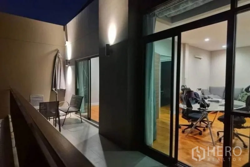 Detached House for rent - Night view of the balcony with wall lights, outdoor chairs and sliding doors opening to living areas.