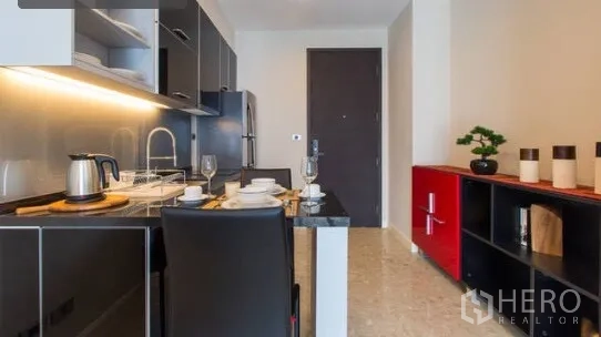 Condominium for rent in Khlong Toei, Bangkok - Open kitchenette with dining for two, entry door, and red storage console.