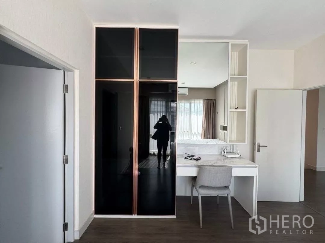 Detached House for rent in Saphan Sung, Bangkok - Bedroom corner with built-in wardrobe, vanity desk and large window with curtains.