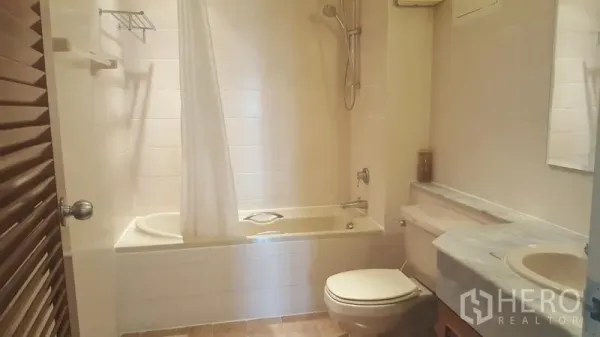 公寓 出租在Watthana, Bangkok - 整洁浴室，浴缸淋浴一体、石材台面洗手盆与瓷砖墙面。